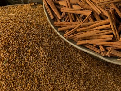 Close-up of cinnamon sticks and seeds at an outdoor spice market.